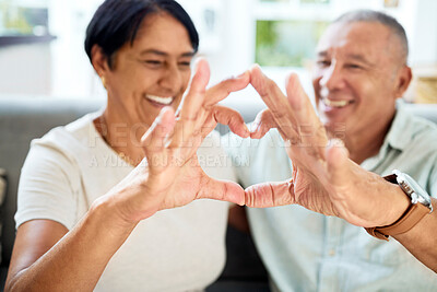 Buy stock photo Mature couple, heart hands and love on home sofa for connection, marriage and bond. A happy man and woman together on a couch with emoji, shape or symbol for commitment, trust or health and wellness