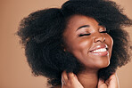 Natural beauty, black woman and hair care for afro, smile and volume on a brown studio background. Aesthetic, hairstyle and African model with cosmetics after salon treatment, wellness and texture