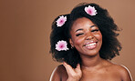 Afro hair, mockup or portrait of black woman with flowers, beauty or smile on a brown studio background. Hairstyle, space or happy African model with aesthetic, wellness or glow with floral plants