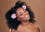 Hair care, flowers and black woman, happy and beauty in studio isolated on a brown background. Smile, floral afro cosmetics or natural African model in organic salon treatment, wellness and hairstyle