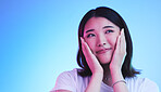 Face, thinking and Asian woman with beauty or dream with hope or smile isolated in a studio blue background. Cute, shy and happy young female person with skincare or soft skin and with a memory
