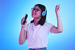 Singing, music and a woman with a phone on a blue background for a podcast, audio or fun. Happy, freedom and a young girl with headphones and a mobile app for radio, karaoke or sound on a backdrop