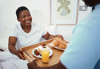 Buy stock photo Happy, morning and a black couple with breakfast in bed for love, care or birthday in a house. Smile, eating and an African man with food for a woman in the bedroom together on holiday or honeymoon