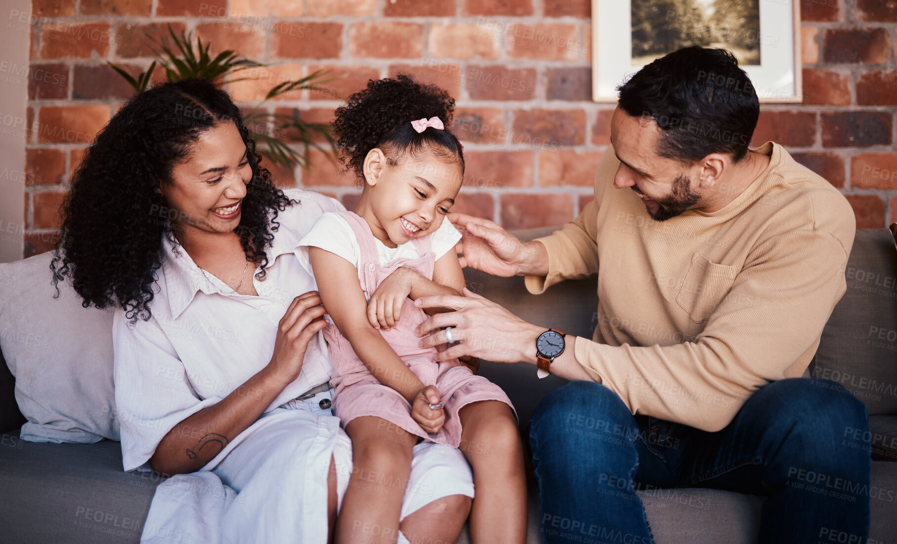 Buy stock photo Family, tickle and laughing while playing on a home sofa for fun, bonding and time together. A happy man, woman or parents and girl kid in lounge with love, care and happiness in house in Puerto Rico