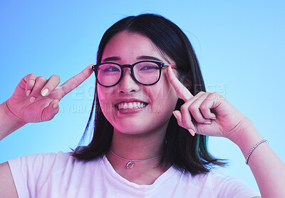 Buy stock photo Portrait, smile and woman with glasses on blue background in studio for optometry style. Happy asian model, gen z girl and face with spectacles for fashion, eye care and lens choice of cool frames 