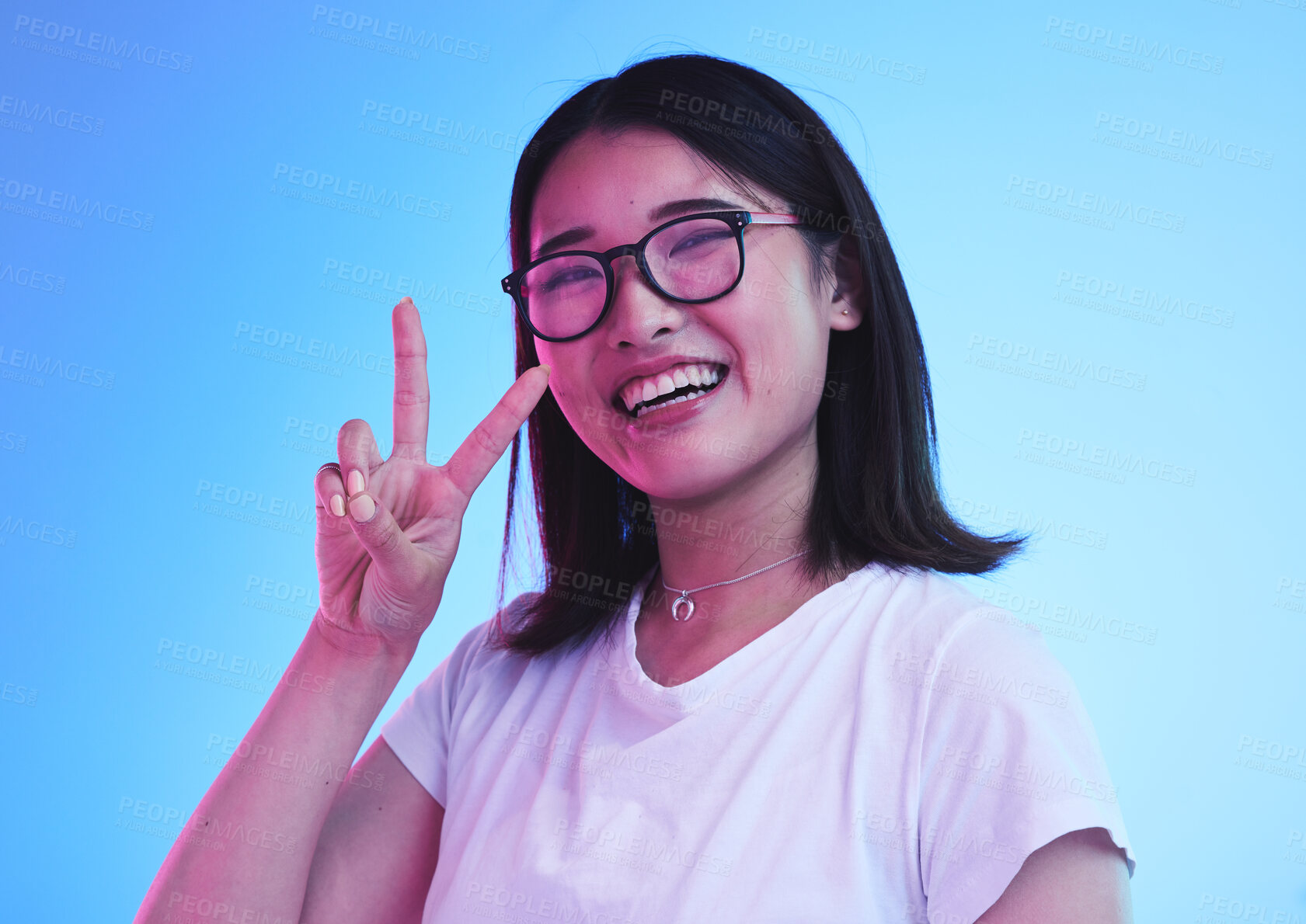 Buy stock photo Peace sign, smile and show with portrait of woman in studio for emoji, like and social media. Happy, support and motivation with face of Asian person on blue background for v symbol, gen z and icon 