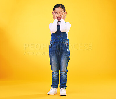 Buy stock photo Excited, happy and hands on face of girl child in studio with news, sale or fashion giveaway on yellow background. Wow, emoji and kid winner with celebration gesture for coming soon surprise prize