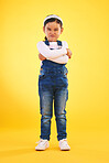 Arms crossed, angry and portrait of girl child in studio with bad, attitude or behavior problem on yellow background. Frown, face and asian kid with body language for no, frustrated or tantrum emoji