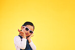 Girl, child and portrait with sunglasses in studio for confidence, cool and positive attitude. Face, space and young kid with mockup, pose and fashion announcement isolated on a yellow background