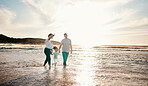 Beach, sunset and family holding hands together on vacation, adventure or holiday together. Travel, having fun and girl child bonding with mother and father on the sand by the ocean on weekend trip.