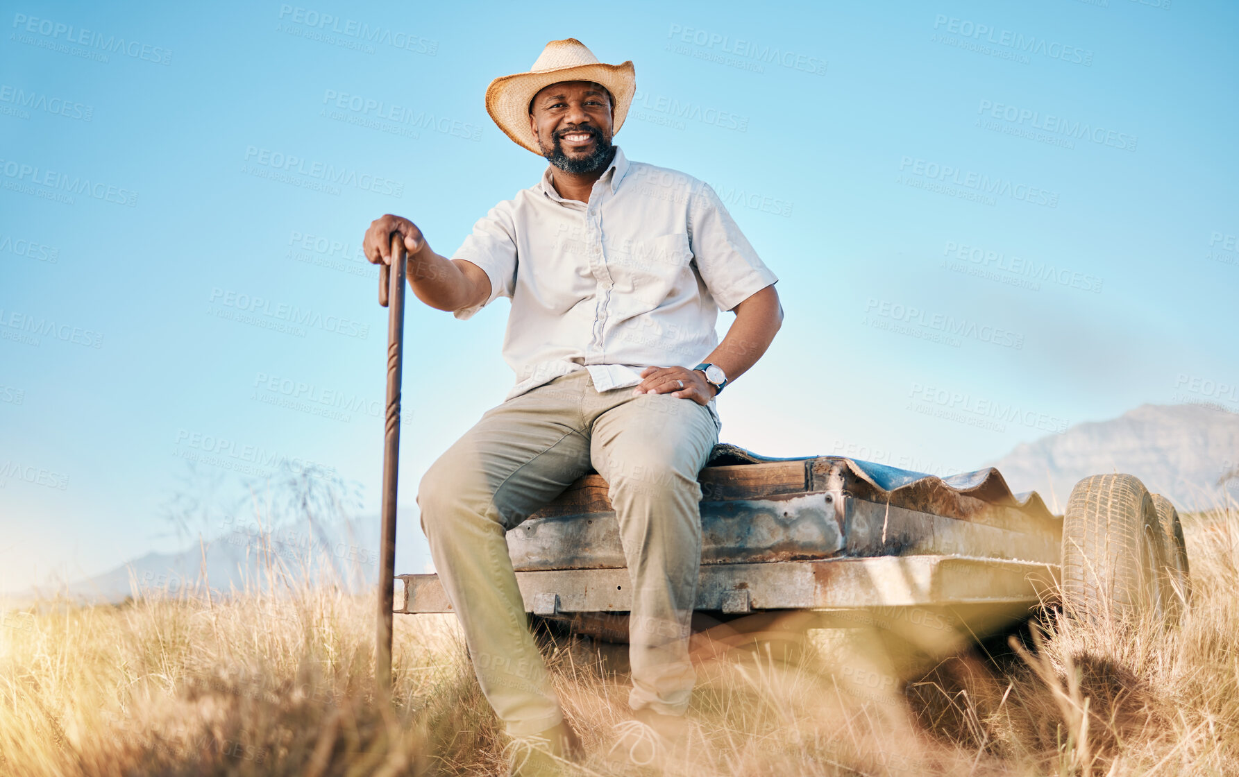 Buy stock photo Happy, African farmer and portrait in the countryside and man, sitting and watching over environment, field and land. Farming, meadow and agriculture worker outdoor with smile or happiness in summer