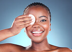 Black woman, portrait smile and cotton pad for makeup removal against a blue studio background. Face of happy African female person with swab in beauty for cleaning, hygiene or facial treatment