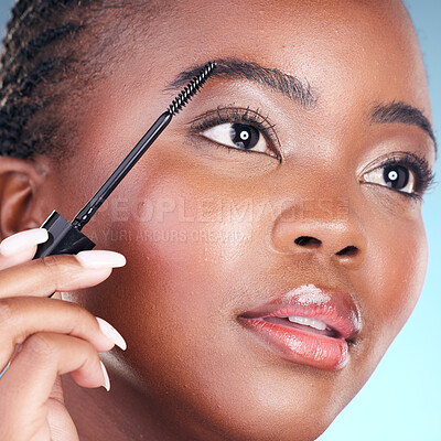 Buy stock photo Studio face, black woman and eyebrow mascara, product or cosmetology tools for facial cosmetics application. Beauty routine, brow care makeup and closeup African person on blue background