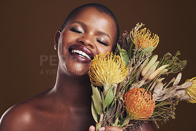 Buy stock photo Aesthetic, beauty and protea with the face of a black woman in studio on brown background for natural treatment. Smile, plant or cosmetics and a young model posing for skincare wellness with flowers