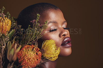 Buy stock photo Black woman, flowers and makeup in studio for beauty, wellness or thinking with protea by brown background. Girl, model and glow on facial skin, sustainable cosmetics and eyes closed for aesthetic