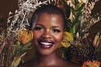 African woman, flowers and makeup in studio portrait with beauty, wellness or natural glow by brown background. Girl, model and face with leaves, plants and happy for cosmetics, skincare or aesthetic