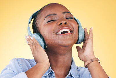 Buy stock photo Singing, music and black woman on headphones, happy and listening in studio isolated on a yellow background. Smile, radio and African person streaming podcast, audio and sound, hearing and freedom.