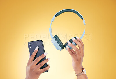 Buy stock photo Hands, phone and headphones for music on a yellow background in studio for a streaming subscription service. Mobile, internet and radio with a person listening to audio through an entertainment app