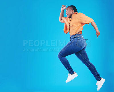 Buy stock photo Jump, black woman and excited with motivation in studio from celebration and smile. Happy, energy and African female person with mockup space and blue background with leap from deal and announcement