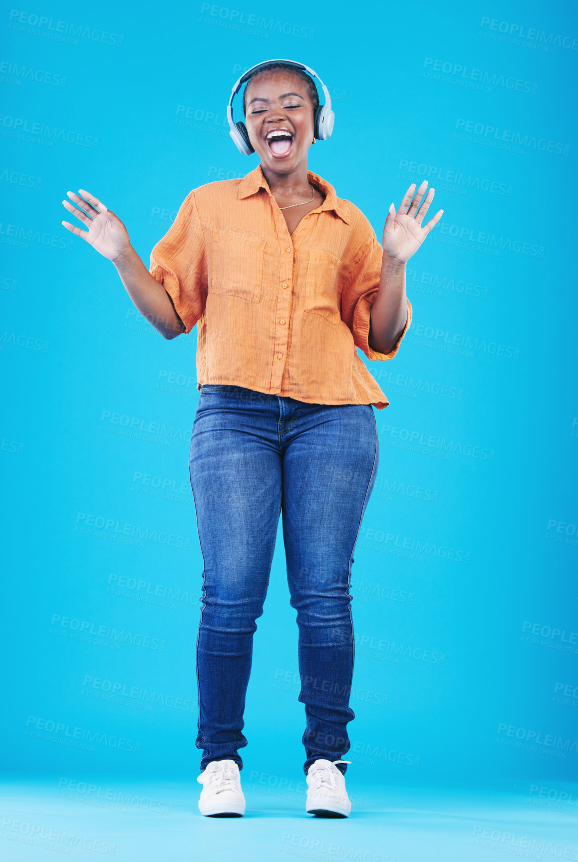 Buy stock photo Black woman, headphones and singing to music with dance in a studio. Audio streaming, radio and happy female person with blue background and excited from celebration and freedom with hip hop song
