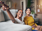 Pointing, friends and women in living room for visit, bonding and conversation in apartment. Hand gesture, showing house decor and black female and Asian person in lounge to relax together on weekend