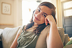 Happy, smile and portrait of woman on a sofa relaxing in the living room of her apartment. Calm, peaceful and face of young female person from Mexico with positive attitude sitting in lounge at home.