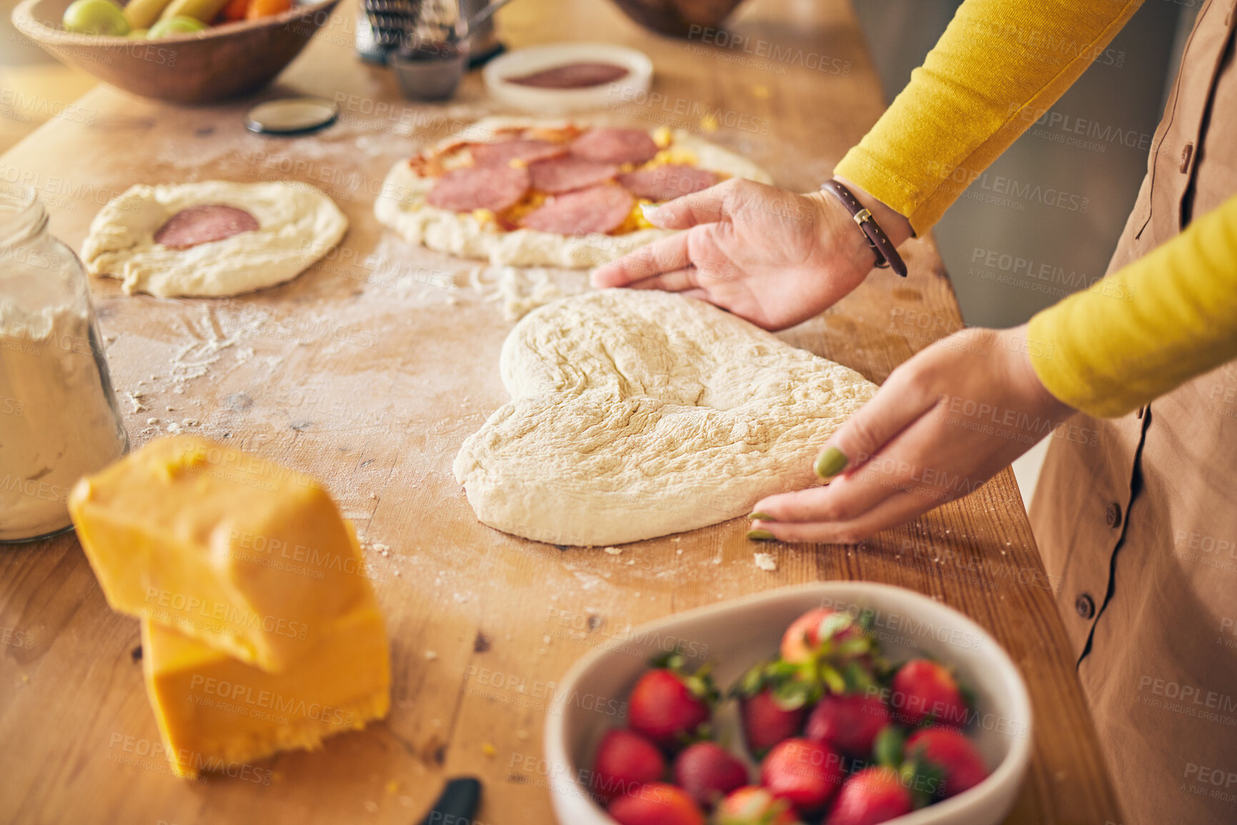 Buy stock photo Pizza, heart with dough and hands on wooden table, person cooking with flour and cheese, fruit and food at home. Nutrition, meal and strawberry in kitchen, baking with ingredients and love sign