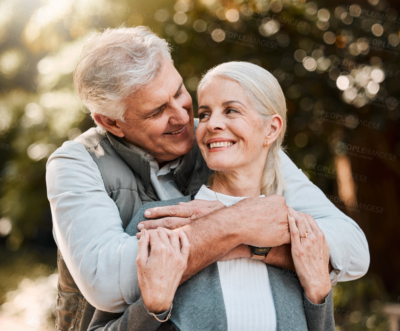 Buy stock photo Love, hug and senior couple at a park happy, free and enjoy travel, holiday or weekend outdoor. Face, smile and elderly man embrace woman in forest, bond and having fun on retirement trip together