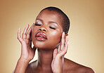 Beauty, makeup and a black woman with hands on face in studio for skin care, glow and cosmetics. Headshot of african person or model with facial shine, eyelash and lipstick on a beige background