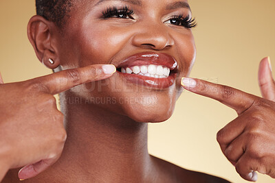 Buy stock photo Smile, beauty and a woman pointing at teeth in studio with skin care, glow and makeup. Face of an African model person with dental shine, dermatology and cosmetics announcement on a beige background