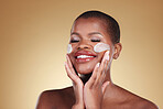 Happy, skincare and black woman with face cream in studio for makeup removal and wellness on brown background. Facial, cleaning and model with moisturizer, exfoliate or beauty, dermatology or mask
