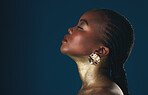 Profile, beauty and black woman in gold for culture, heritage or tradition on a blue background in studio. Face, mockup and african style with a young model closeup for elegance or cosmetics