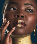 Face, beauty and black woman in gold for culture, heritage or tradition on a blue background in studio. Skincare, makeup and african style with a young model closeup for elegance or cosmetics