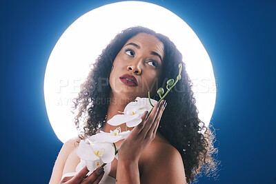 Buy stock photo Beauty, circle light and woman with flowers for wellness, natural cosmetics and skincare in studio. Spa, neon aesthetic and person with orchid for makeup, face glamour and facial on blue background