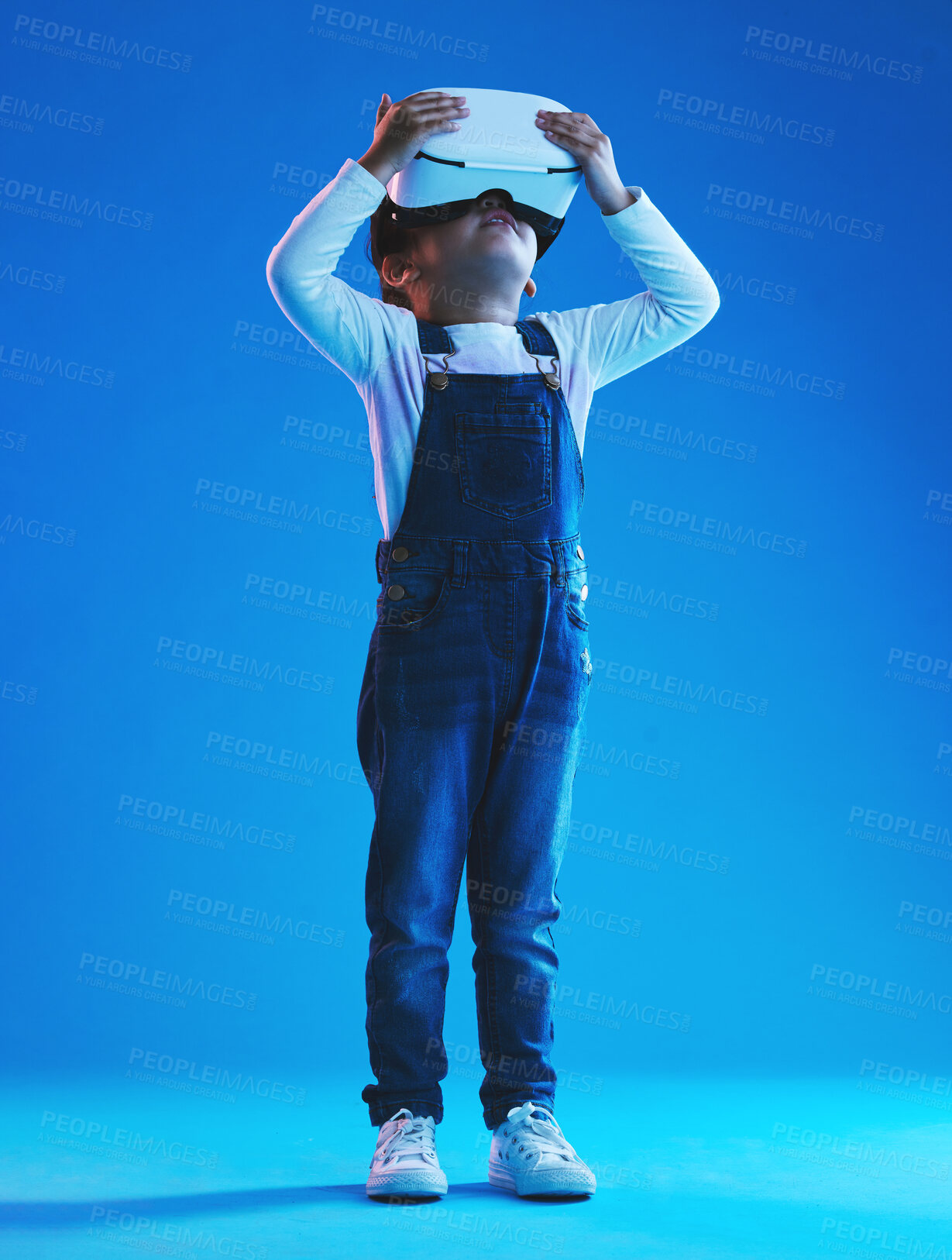 Buy stock photo Glasses, virtual reality and metaverse with girl, futuristic and digital transformation on a blue studio background. Kid, person and model with vr headset for video games, future or augmented reality