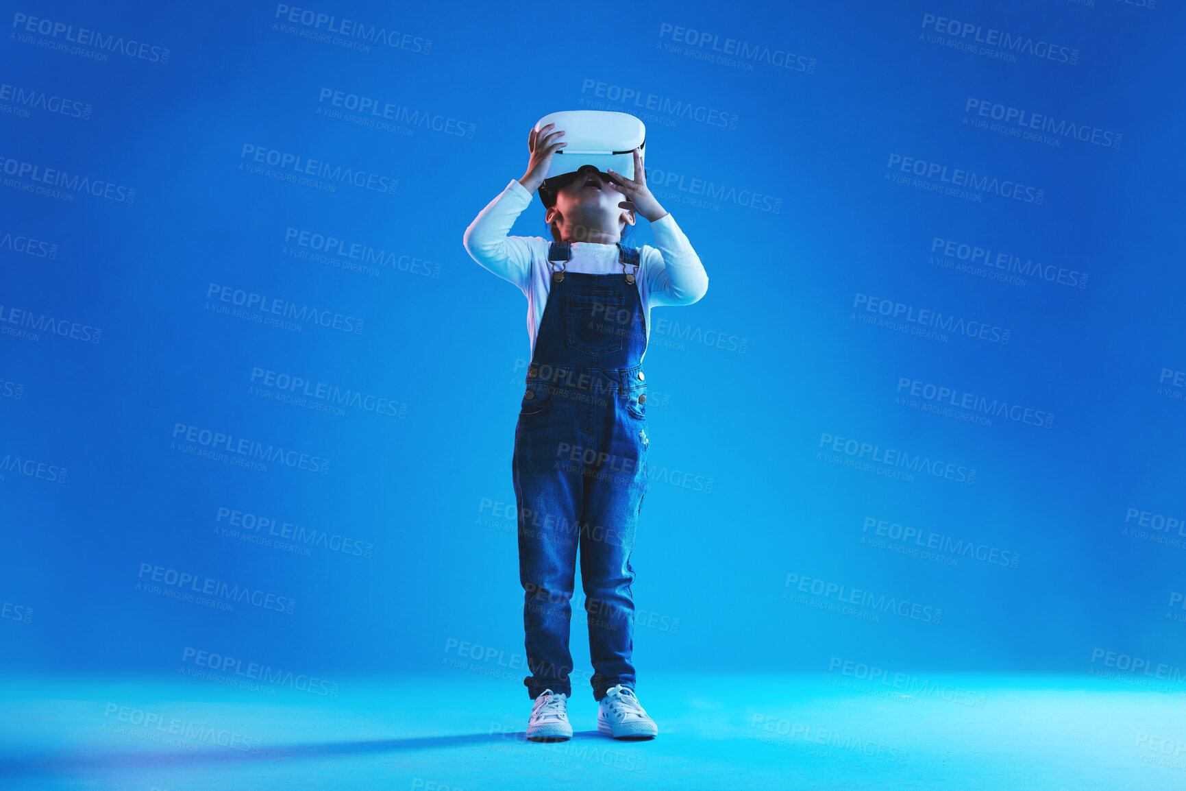 Buy stock photo Glasses, virtual reality and metaverse with girl, online games or digital transformation on blue studio background. Kid, child and model with vr headset with technology, futuristic and live streaming