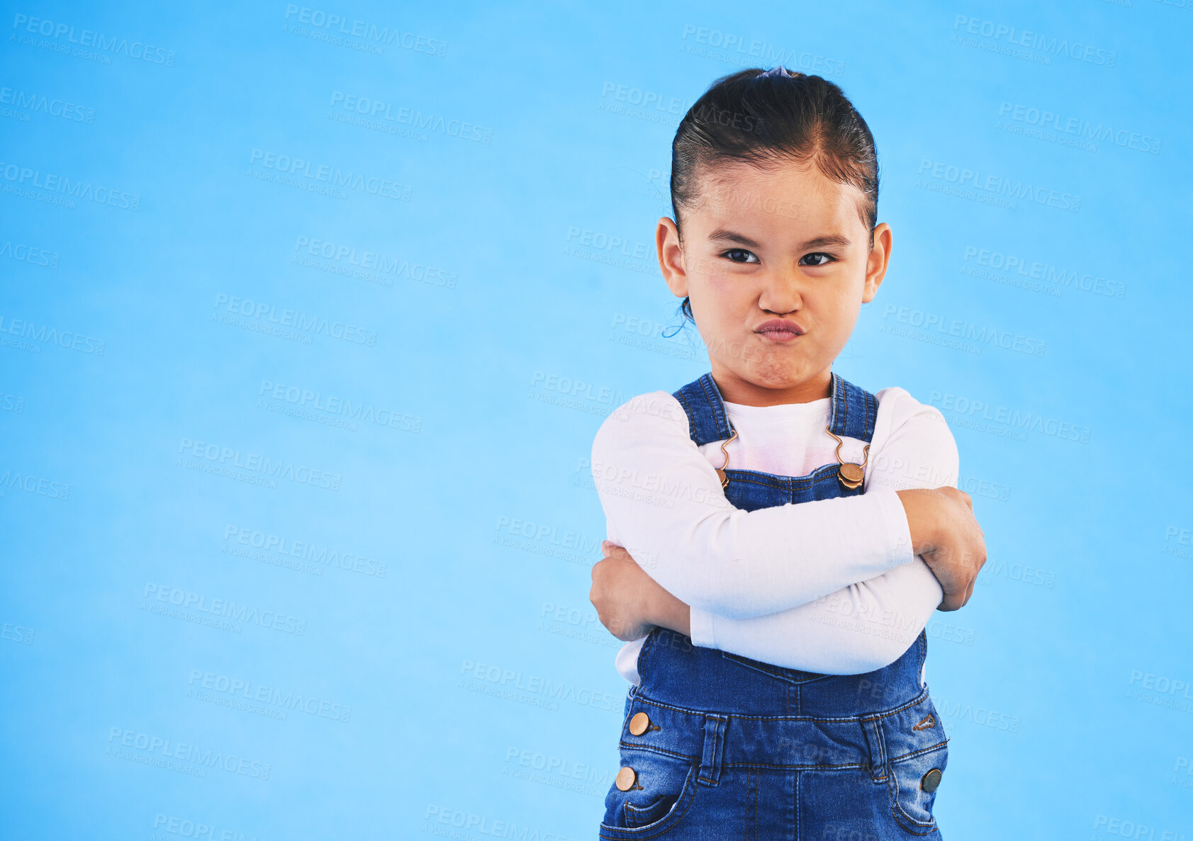 Buy stock photo Angry, child and arms crossed with tantrum in studio with mockup space. Kid, young girl and frustrated with cross frown and pout with a problem and mad attitude with blue background and grumpy