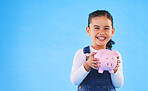 Girl kid, piggy bank and studio portrait with mockup space, saving and financial education by blue background. Female child, money box and excited for goal, investing or learning discipline with cash