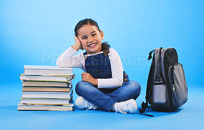 Buy stock photo Girl child, sitting and books in studio portrait, backpack and excited for learning on floor by blue background. Female kid, education and development with smile, future and studying for knowledge