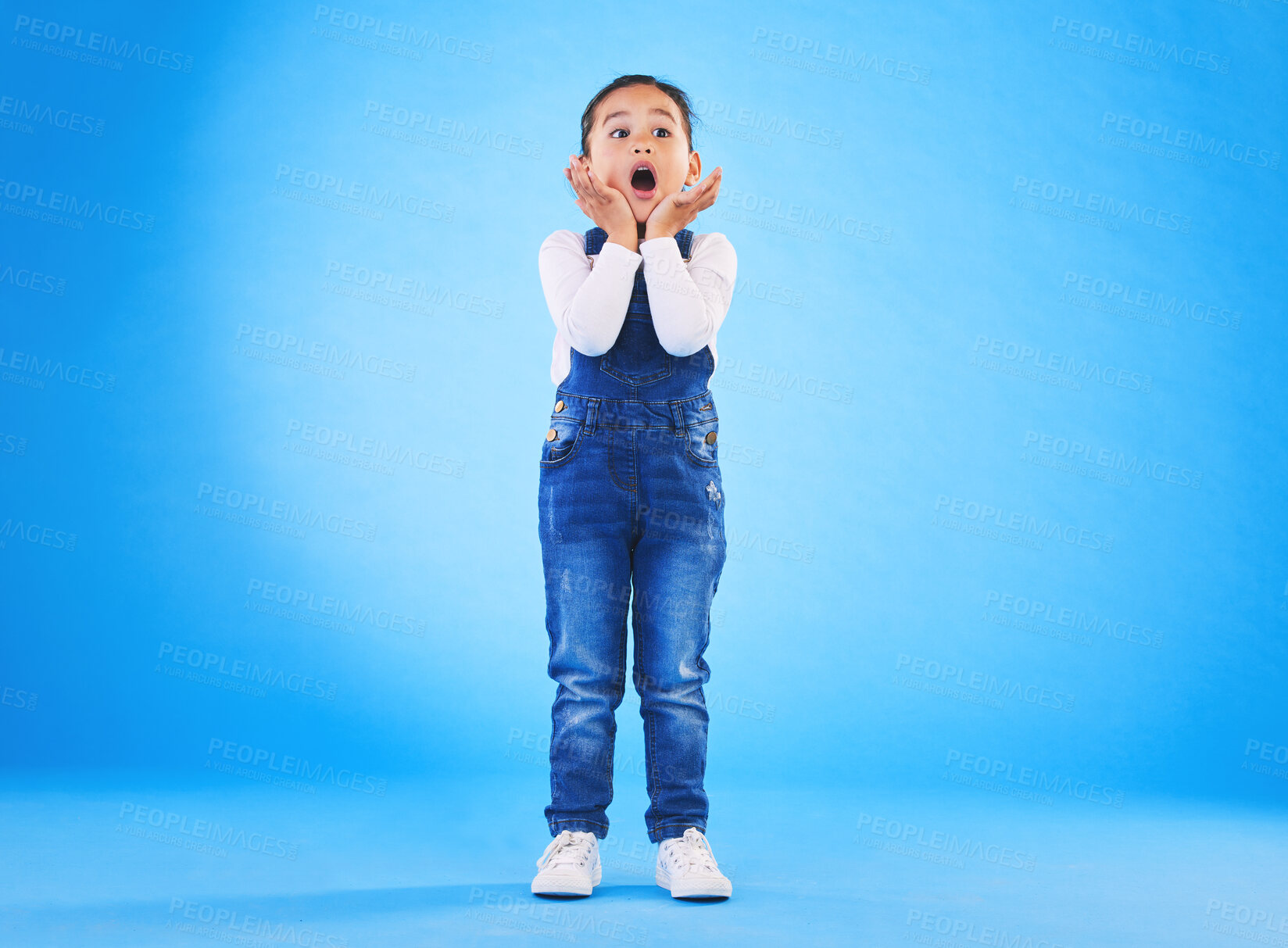 Buy stock photo Shocked, wow and girl surprise with hands to face in studio with fear and scared from danger. Alarm, blue background and young child from Hawaii with scary, omg and emoji face of a kid in danger