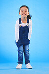 Excited girl child, fashion and studio portrait with jeans, dungaree and trendy style by blue background. Female kid model, smile and happy for clothes, aesthetic and youth culture by backdrop