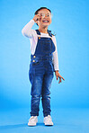 Girl child, glasses and smile in studio with vision, health and thinking for eye care by blue background. Female kid, test spectacles and young fashion model with lens, frame and excited for wellness