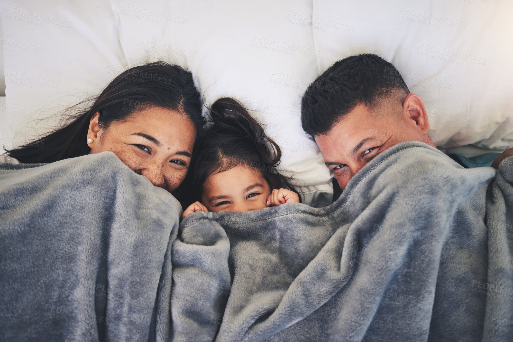 Buy stock photo Happy, hide and relax with family in bed for morning, wake up and playful from above. Love, care and bonding with parents and child in bedroom at home for weekend, resting and happiness together