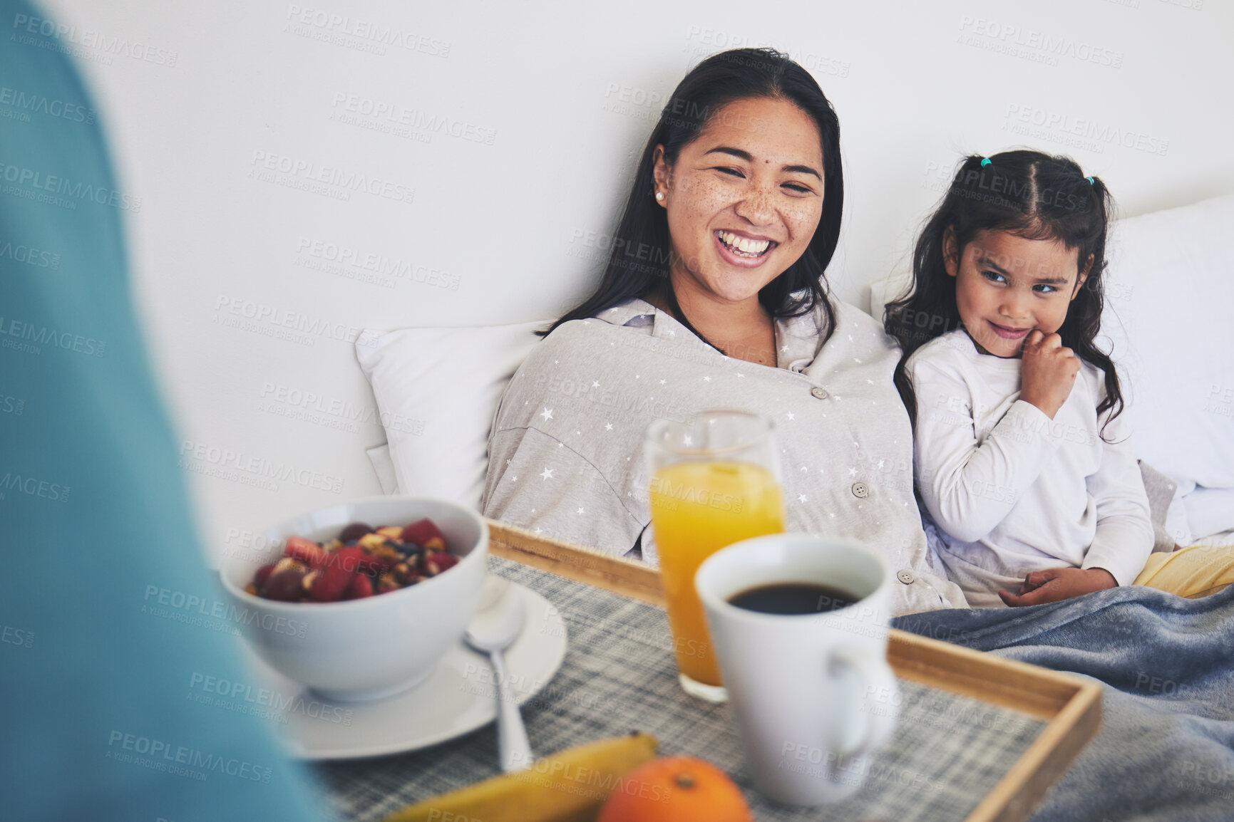 Buy stock photo Mother and daughter with breakfast in bed while relaxing for mothers day surprise at home. Happy, smile and young mom resting with girl child with a healthy meal for brunch on weekend at their house.