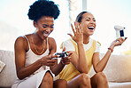 Women on sofa playing video game, laughing and relax in home living room together on internet with controller. Online gaming, esports and happy gamer girl friends on couch on virtual app in apartment