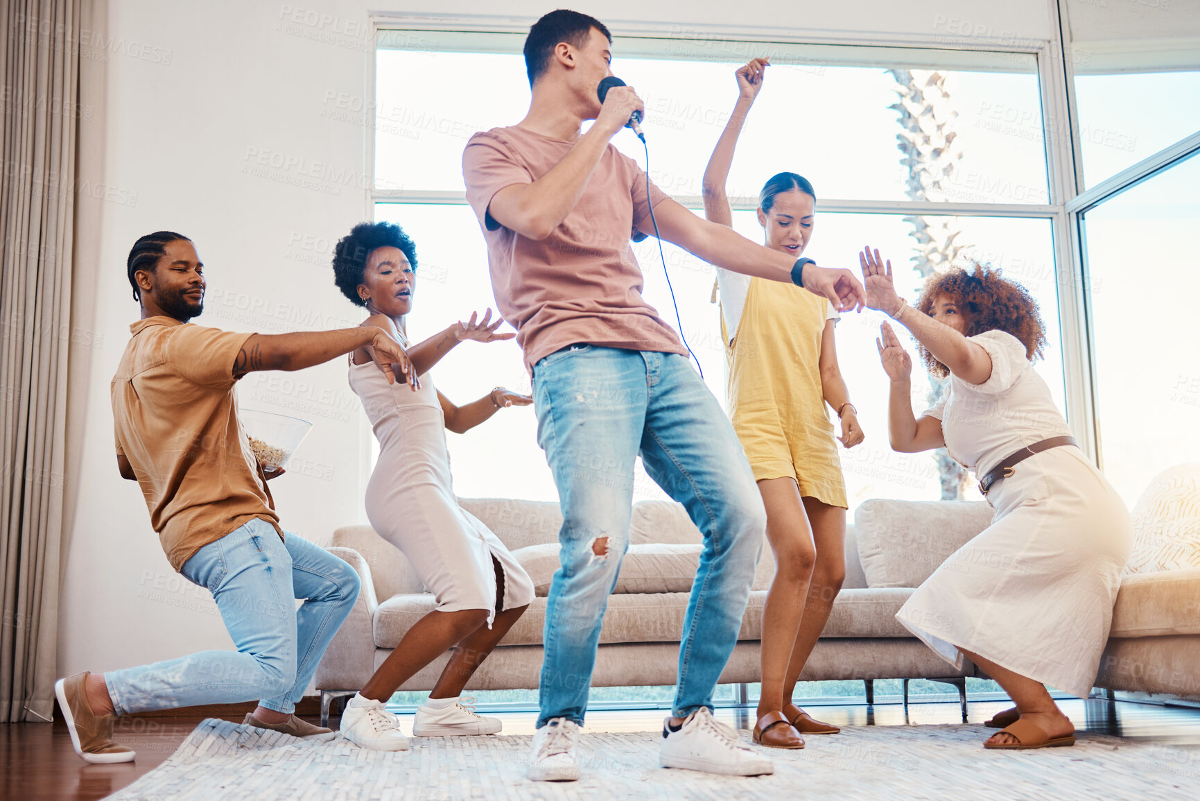 Buy stock photo Karaoke, group and friends singing in the living room with a microphone to music, playlist or radio. Happy, diversity and young people dancing, bonding and having fun together with a song at home.