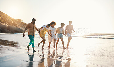 Buy stock photo Summer, holding hands and sunset with friends at beach for freedom, support and travel. Wellness, energy and happy with group of people walking by the sea for peace, adventure and vacation together