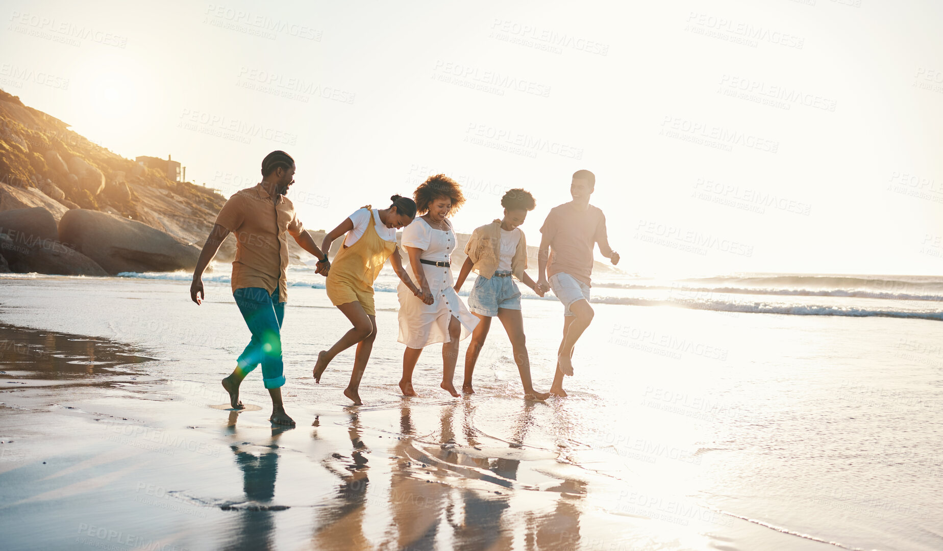 Buy stock photo Summer, holding hands and sunset with friends at beach for freedom, support and travel. Wellness, energy and happy with group of people walking by the sea for peace, adventure and vacation together