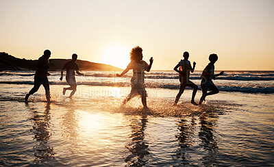 Buy stock photo Sunset, beach and friends with freedom, running and having fun in water together on summer vacation. Ocean, silhouette and group of people at the sea for holiday, bond and travel celebration in Bali