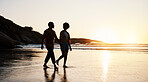 Beach, sunset and silhouette couple walking on sand, holding hands and enjoy romantic time together. Wellness, summer freedom and dark shadow of people bonding, talking and relax on tropical date